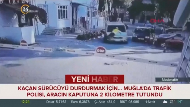 Trafik polisi, kaan srcy durdurmak iin aracn kaputuna 2 kilometre tutundu